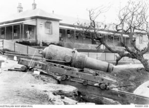 1895. A 9 inch, 12 ton rifled muzzle loading (RML) gun being moved at the long course of the NSW school of gunnery at South Head. The main barrack block is in the background.